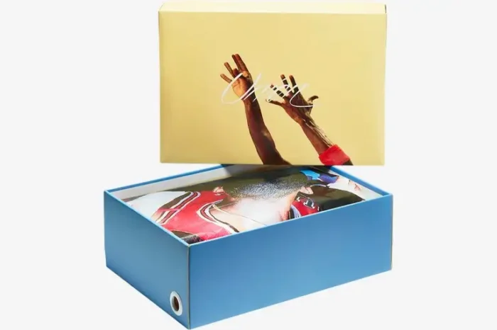 Angled view of the Air Jordan 4 x Union LA Guava Ice shoebox featuring a yellow lid and blue base. - SKU DC9533-800