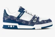 Side profile of a Louis Vuitton LV Trainer sneaker in white leather and blue monogram denim. - SKU 1A9JGR