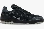 Side profile of a Louis Vuitton LV Trainer sneaker in black and white monogram denim. - SKU 1ACFS1