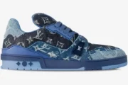 Side view of Louis Vuitton Trainer Monogram Denim Blue sneaker with textured denim and blue sole. - SKU 1AC4YN