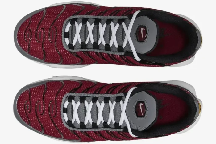 Top-down view of Nike Air Max Plus sneakers in red, grey, and white with black wavy overlays. - SKU DQ3983-600