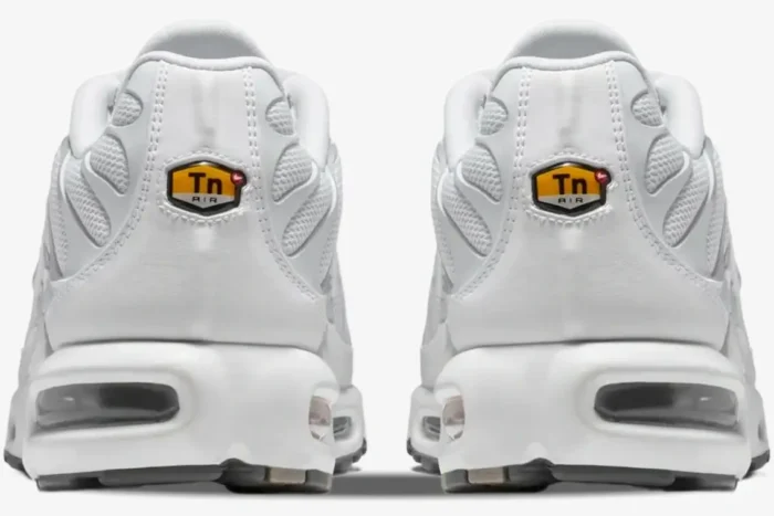 Rear view of Nike Air Max Plus Triple White sneakers showing the yellow Tn Air logo on the heels. - SKU 604133-139