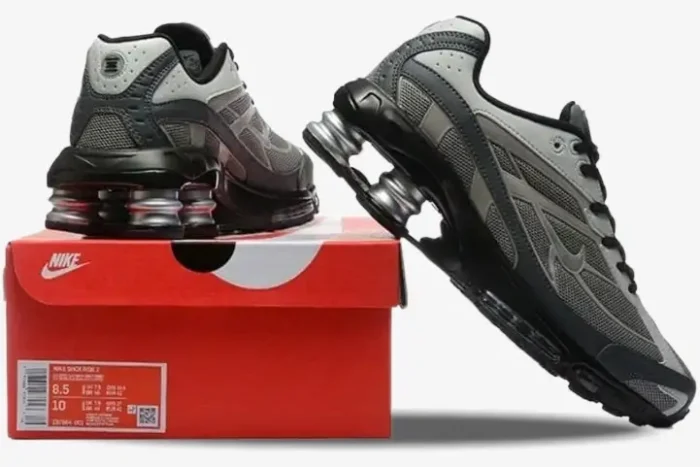 Nike Shox Ride 2 sneakers in light graphite and black, showing rear and side profile views on a red box. - SKU IB4470-099