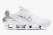 Side profile of Nike Shox TL sneakers in white and metallic silver featuring full-length cushioning columns. - SKU AV3595-100
