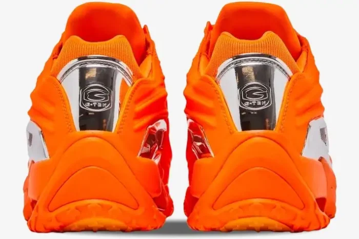 Rear view of bright orange Nike Hot Step 2 x NOCTA sneakers with silver metallic heel plates. - SKU DZ7293-800