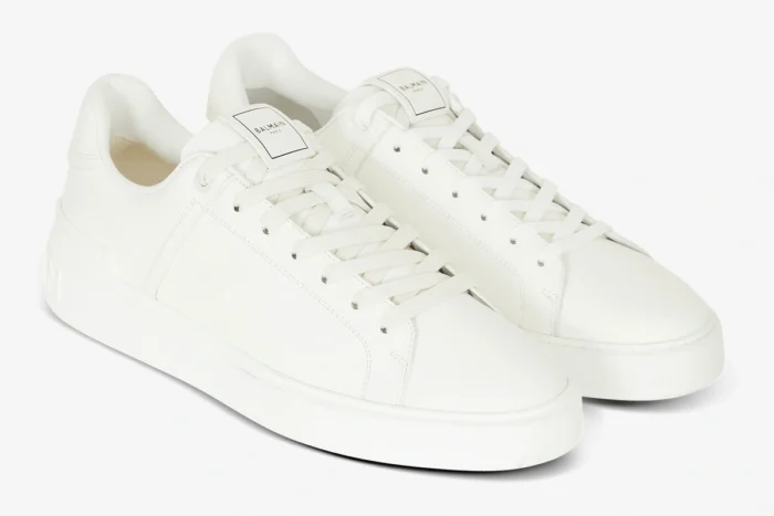 Pair of white Balmain B-Court calfskin trainers shown from a three-quarter front angle. - SKU GM1VI288LVTR