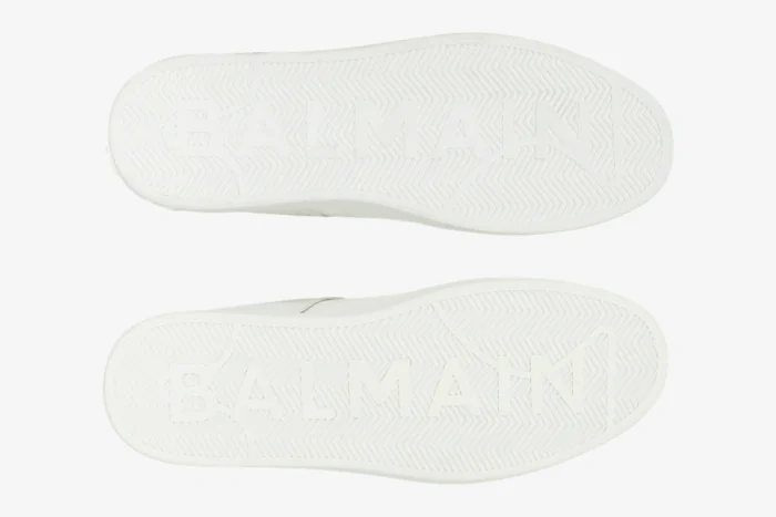 Underside view of white Balmain B-Court Trainer soles with embossed logo and herringbone pattern. - SKU GM1VI288LVTR