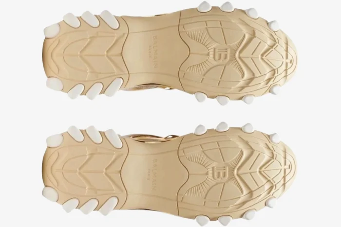 Bottom view of Balmain B-East B3V27 sneakers in beige and gold showing the textured rubber soles. - SKU B3V27