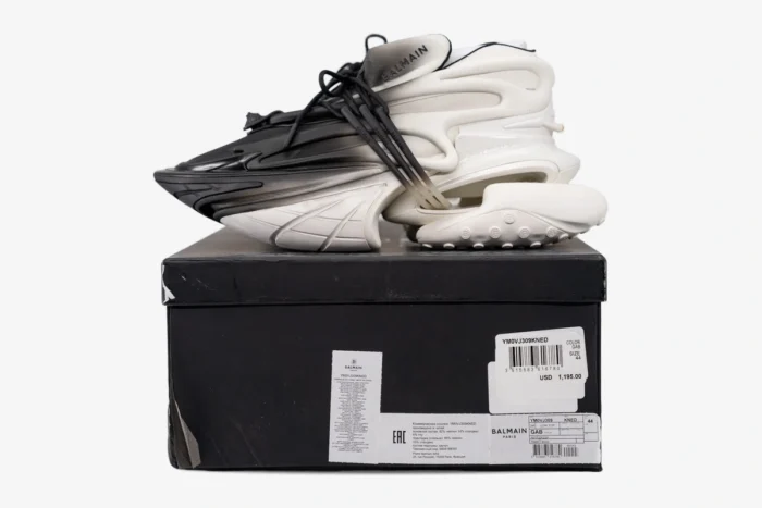 Balmain Unicorn Low Top white and black gradient sneakers on a black box, side profile view. - SKU YM0VJ309KNED-GAB