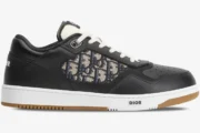 Dior B27 low-top sneaker in black leather with beige oblique motif, shown from a side profile view. - SKU 3SN272ZIR_H965