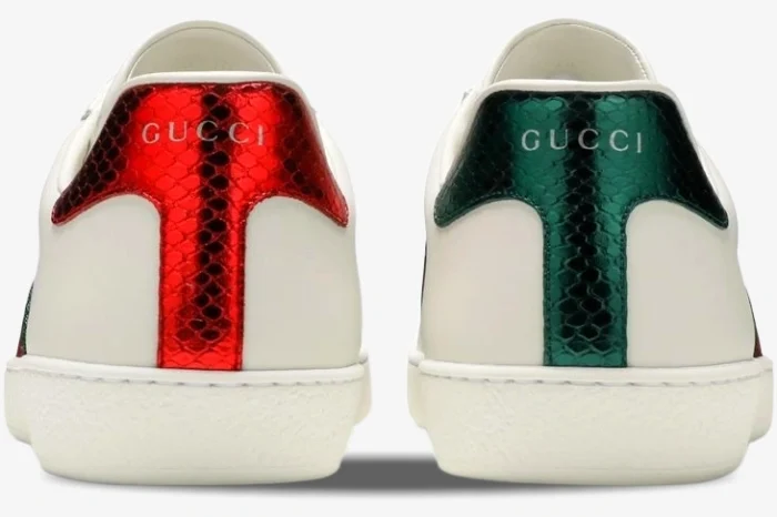 Back view of Gucci Ace white leather sneakers with mismatched metallic red and green snakeskin heel tabs. - SKU 42944602JP09064