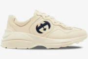 Side view of a Gucci Rhyton sneaker in ivory leather featuring a navy blue interlocking G logo. - SKU 757857UPG709567