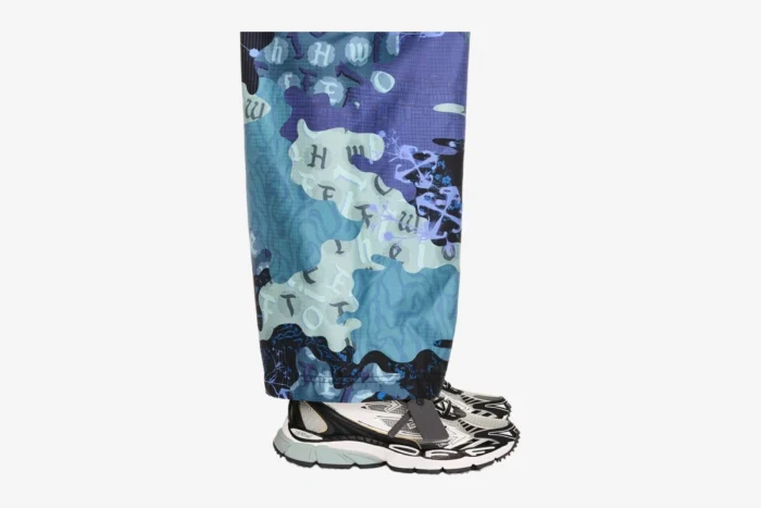 Side view of Off-White Be Right Back sneakers in black, white, and grey, worn with patterned blue pants. - SKU OMIA295C99FAB0010510