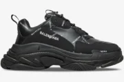 Side view of Balenciaga Triple S Sneaker in black with allover white logo print and chunky layered sole.