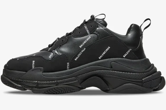 Black Balenciaga Triple S sneaker with allover white logos, side profile view.