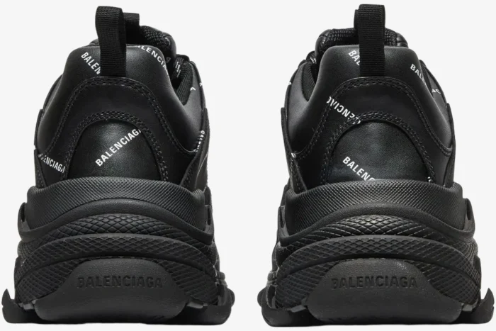 Rear view of black Balenciaga Triple S sneakers with allover white logo print.