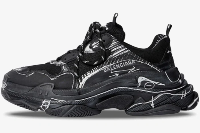Side profile of a black Balenciaga Triple S sneaker with white sketch-style graphic details.