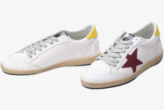 Golden Goose Ball Star white leather sneakers with a red star and yellow heel tab, three-quarter front view. - SKU GMF00117.F002558.10915