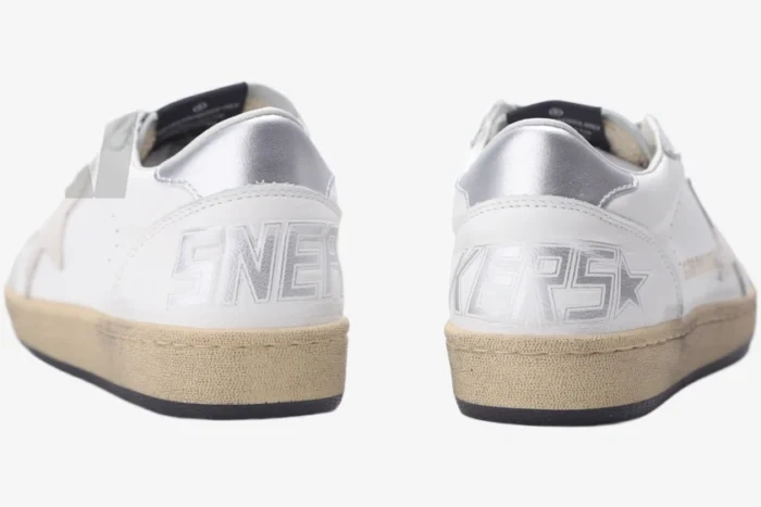 Rear view of Golden Goose Ball Star white and silver distressed leather sneakers with SNEAKERS text on heels. - SKU GWF00117.F002570.10925