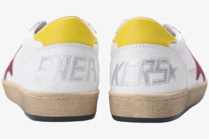 Rear view of Golden Goose Ball Star white leather sneakers with yellow heel tabs and silver SNEAKERS text. - SKU GMF00117.F002558.10915