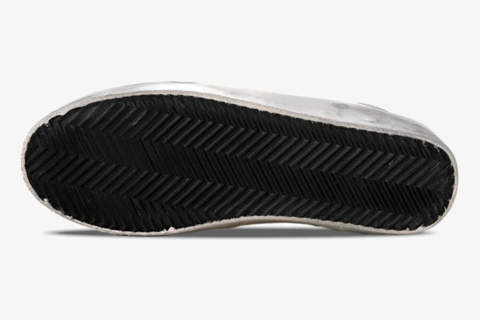 Bottom view of Golden Goose Super-Star sneakers showing black herringbone rubber soles and distressed edges. - SKU GMF00101.F000312.10273