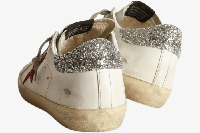 Rear view of white Golden Goose Super-Star sneakers with silver glitter heel tabs and a red glitter star detail. - SKU GWF00101.F000312.10273