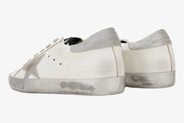 Rear view of Golden Goose White and Silver Super-Star sneakers with distressed soles and glitter heel tabs. - SKU GMF00101.F000312.10273