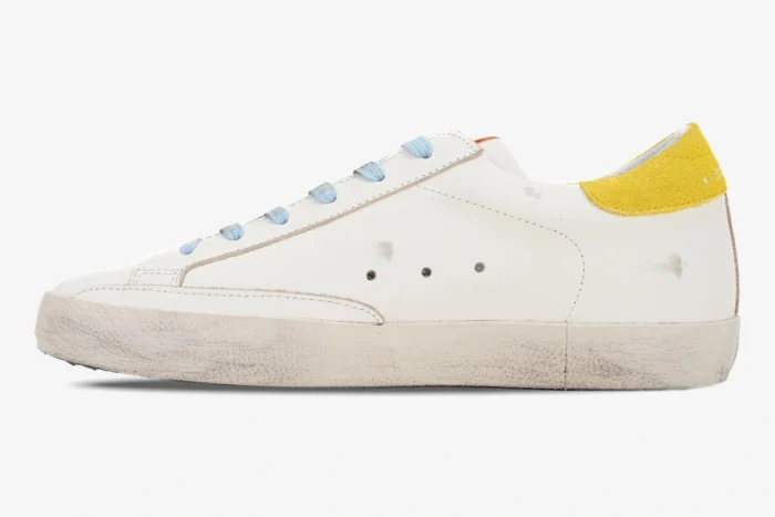 Side profile of a white Golden Goose Super-star sneaker with yellow heel tab and blue laces. - SKU GWF00101.F002559.10928
