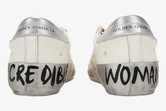 Rear view of white Golden Goose Superstar Incredible Woman sneakers with silver heels and black handwritten text. - SKU GWF00101.F001241.80185