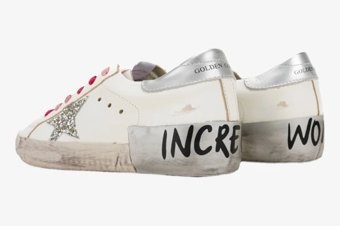 White Golden Goose Superstar sneakers with pink laces, silver glitter star, and 'INCREDIBLE WOMAN' text, side-back view. - SKU GWF00101.F001241.80185