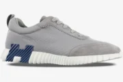 Hermès Bouncing Sneakers in grey mesh and suede with a blue H logo and white ribbed sole, side view. - SKU H202934ZH
