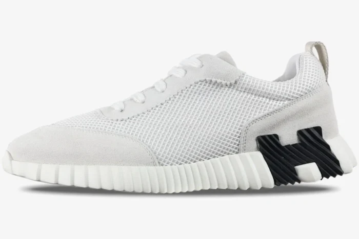 Side profile of Hermes Bouncing Sneakers in white mesh and suede with a black H logo on the sole. - SKU H202934ZH