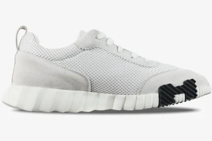 Side profile of Hermes Bouncing Sneakers in white mesh and grey suede with a black rubber sole detail. - SKU H202934ZH