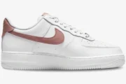 Side profile of a white Nike Air Force 1 Low sneaker with a rust pink swoosh and heel tab. - SKU CZ0270-103