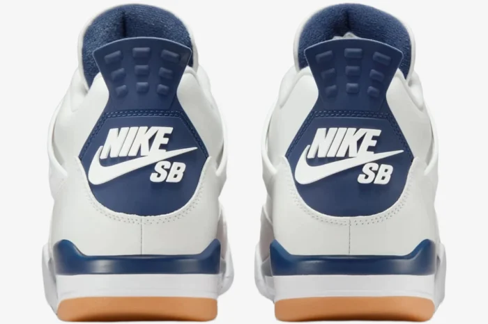 Rear view of white and navy Nike SB Jordan 4 sneakers with blue heel tabs and gum rubber outsoles. - SKU DR5415-100